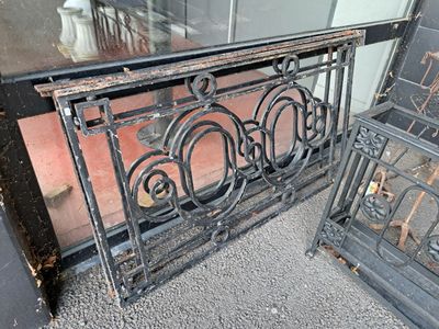 une clôture en fer noir située à l'extérieur d'un bâtiment