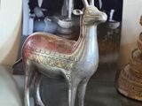 a silver deer statue sitting on a table next to a clock