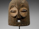 un masque en bois représentant un visage, posé sur un socle