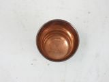 a small copper bowl sitting on a white surface