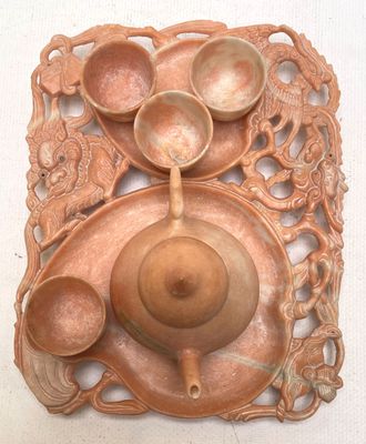 a wooden plate with a teapot and bowls on it