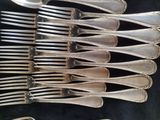 a lot of silver forks and spoons sitting on a table