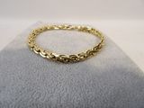 a yellow gold bracelet on a white background
