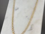 un collier orné de perles d'or posé sur un socle en marbre