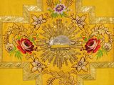 embroidered cross with gold and red flowers on a yellow background
