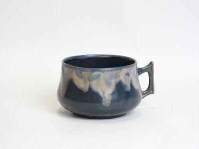 a blue cup with a handle on a white surface