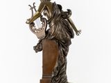 a bronze statue of a woman playing a harp on a marble base