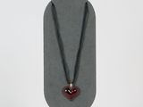 collier avec un cœur rouge sur un cordon noir, sur fond blanc
