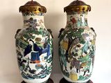 une paire de vases chinois ornés de scènes asiatiques, posés sur une surface blanche