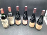 six bottles of wine are lined up in a row on a counter