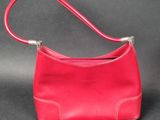 a red purse with a long strap on a black background