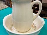 a white pitcher sitting on top of a bowl on a table