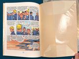 a person holding a comic book open on a table