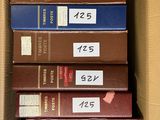several books are stacked in a cardboard box with labels on them