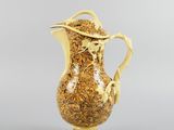 an image of a gold and white pitcher on a gray background