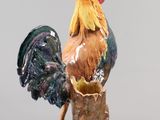 a figurine of a rooster sitting on top of a tree stump
