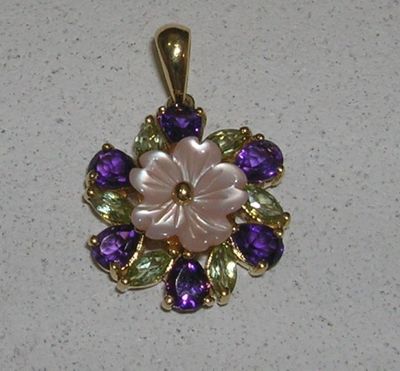 une image représentant un pendentif en forme de fleur violette et verte sur un fond blanc