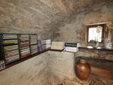 a room with a stone wall and a shelf with books