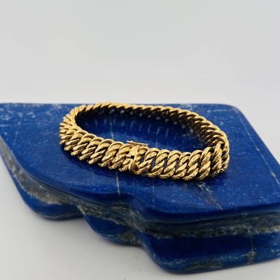 a close up of a gold bracelet on a blue stone