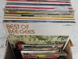 une boîte en carton remplie de disques de toutes sortes, posée par terre