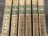 six old books sitting on top of a table next to each other