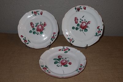 trois assiettes ornées de roses sont posées sur une table