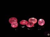 trois diamants roses sur une surface noire, avec un fond noir