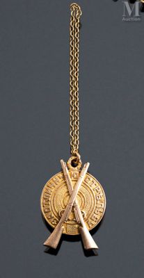 a close up of a gold necklace with two crossed swords on it