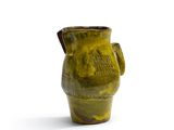 un vase vert muni d'une anse sur fond blanc