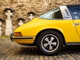 a yellow car parked in front of a brick wall