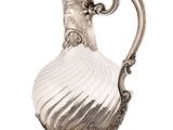 an antique silver plated pitcher on a stand on a white background
