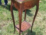 une petite table en bois avec une étagère, posée sur l'herbe