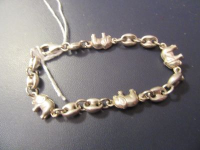 un bracelet en argent orné d'une breloque en forme de chat, posé sur une table