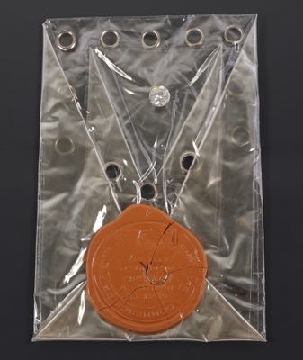 an orange medal in a clear bag on a black surface