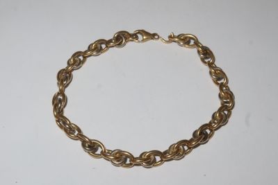 a close up of a gold chain bracelet on a white surface
