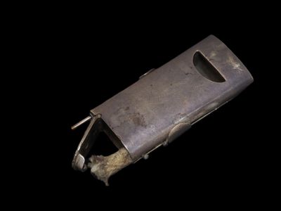 un objet métallique percé d'un trou, sur fond noir
