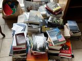 a cat sitting on the floor next to a pile of books