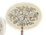 two small hand fans with floral designs on them sitting next to each other