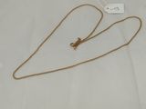 a close up of a gold necklace on a white surface