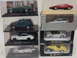 Quatre modèles différents de voitures sont exposés dans des vitrines posées sur une table