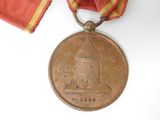 a medal with a red ribbon around it on a white surface
