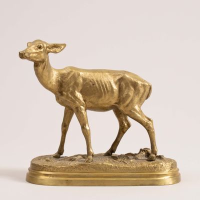 gold deer figurine standing on a base on a white background