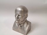 statue of a bust of a man in a suit on a white surface