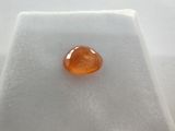 a close up of an orange gemstone on a white surface