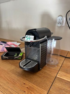 une cafetière noire posée sur une table en bois, à côté d'une tasse