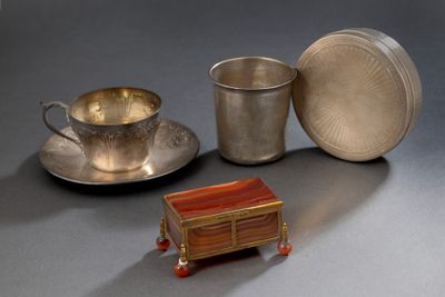 une tasse et une soucoupe en argent posées sur une table, à côté d'une assiette en argent