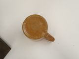a brown cup sitting on a white surface next to a hammer