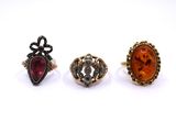 three rings, one with an orange stone and one with a red stone