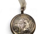 a silver medal with a picture of a man on a horse on it