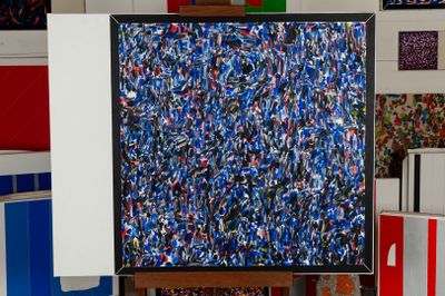 a painting on a easel in a room with many different colored boxes